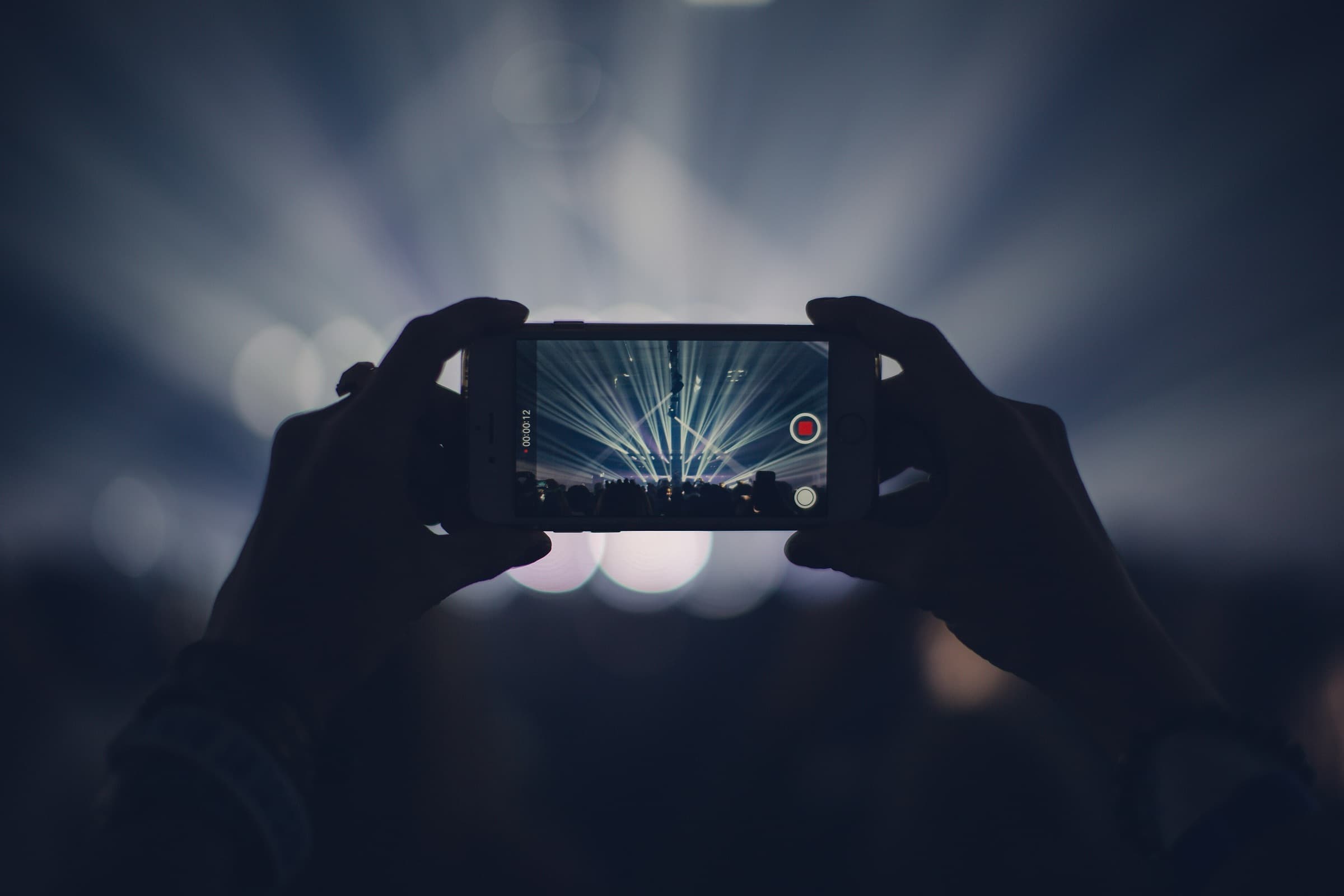 Two hands holding up a phone, recording a concert