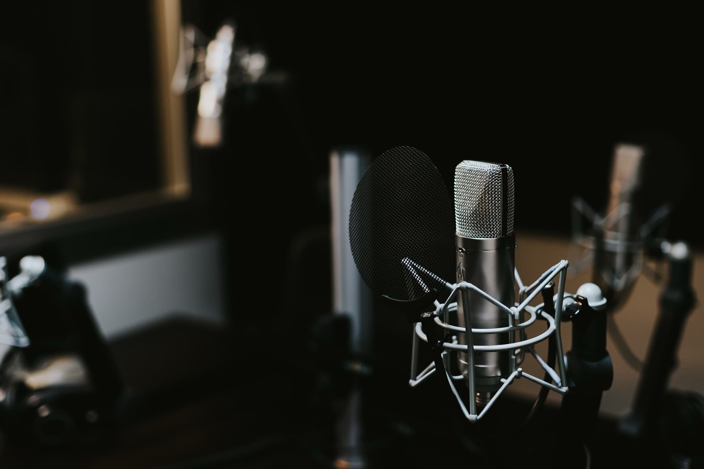 A condenser microphone with a pop filter in a dim recording studio